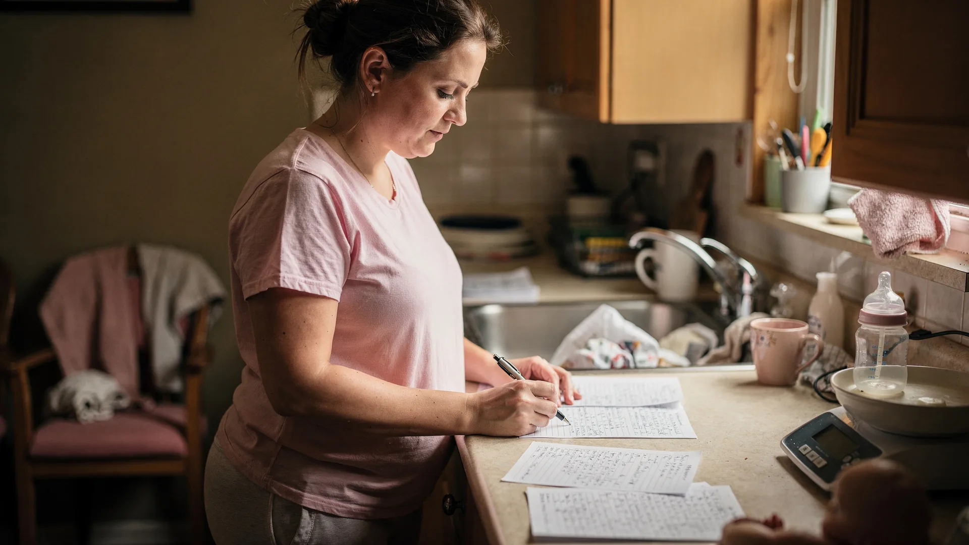 A woman reviews printed notes at a kitchen counter while a scale sits tucked away in the background.